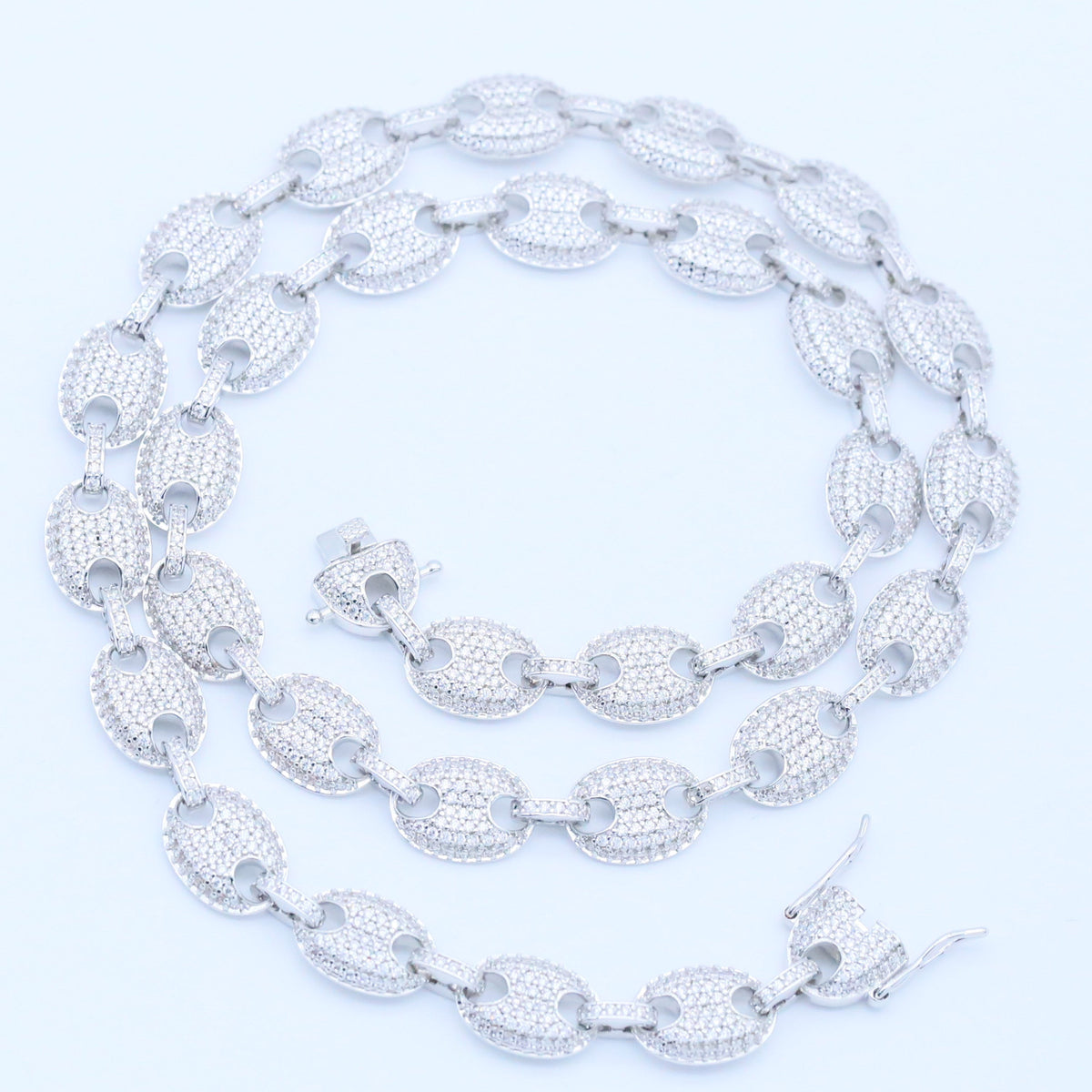 Silver-tone stone-set oval-link jewelry coiled on a white background