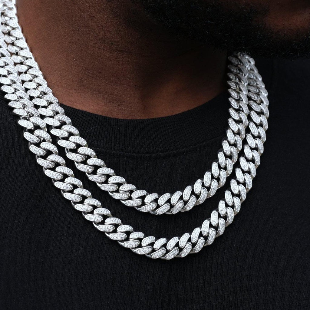 Layered silver-tone iced Cuban link chains over a black shirt