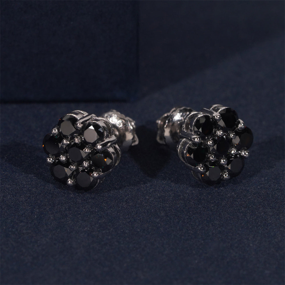Black flower stud earrings in a silver-tone setting on dark fabric