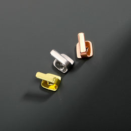Gold, Silver and Rose Gold bar tooth caps on a gray surface