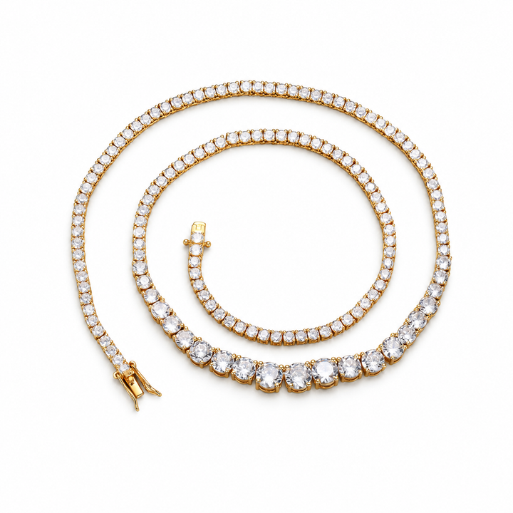Gold-tone graduated tennis necklace coiled on white with its clasp open