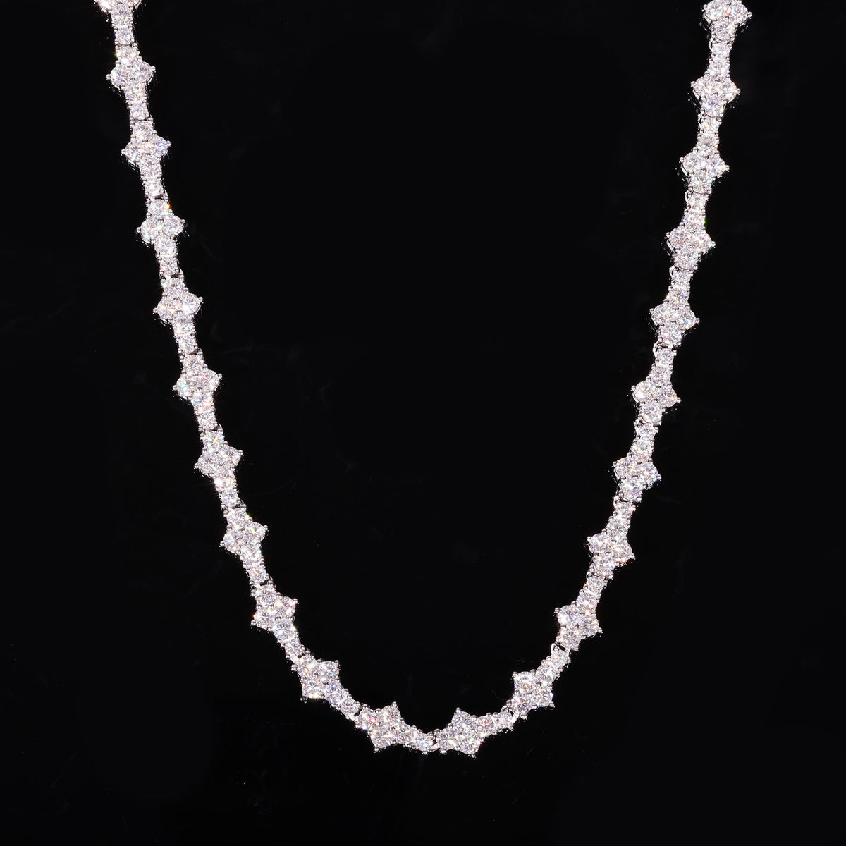 Silver-tone moissanite tennis chain with angular settings draped against black