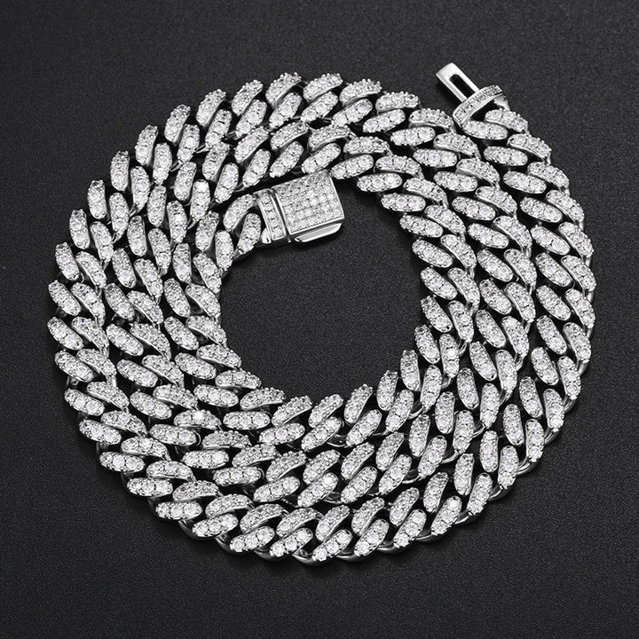 Silver-tone single-row moissanite Cuban chain coiled on black fabric with an open clasp