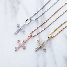 Silver gold and rose gold iced ornate cross pendants on marble