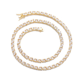 Gold-tone triangle tennis chain coiled on white with its open clasp visible