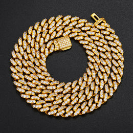 Gold-tone single-row moissanite Cuban chain coiled on black fabric with an open clasp