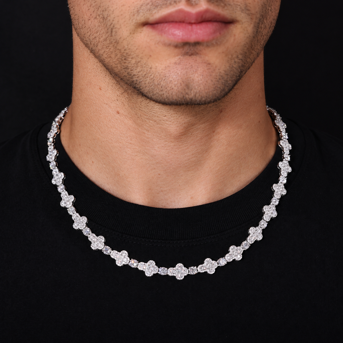 Model wearing a silver-tone moissanite cross tennis chain with a black crew-neck shirt