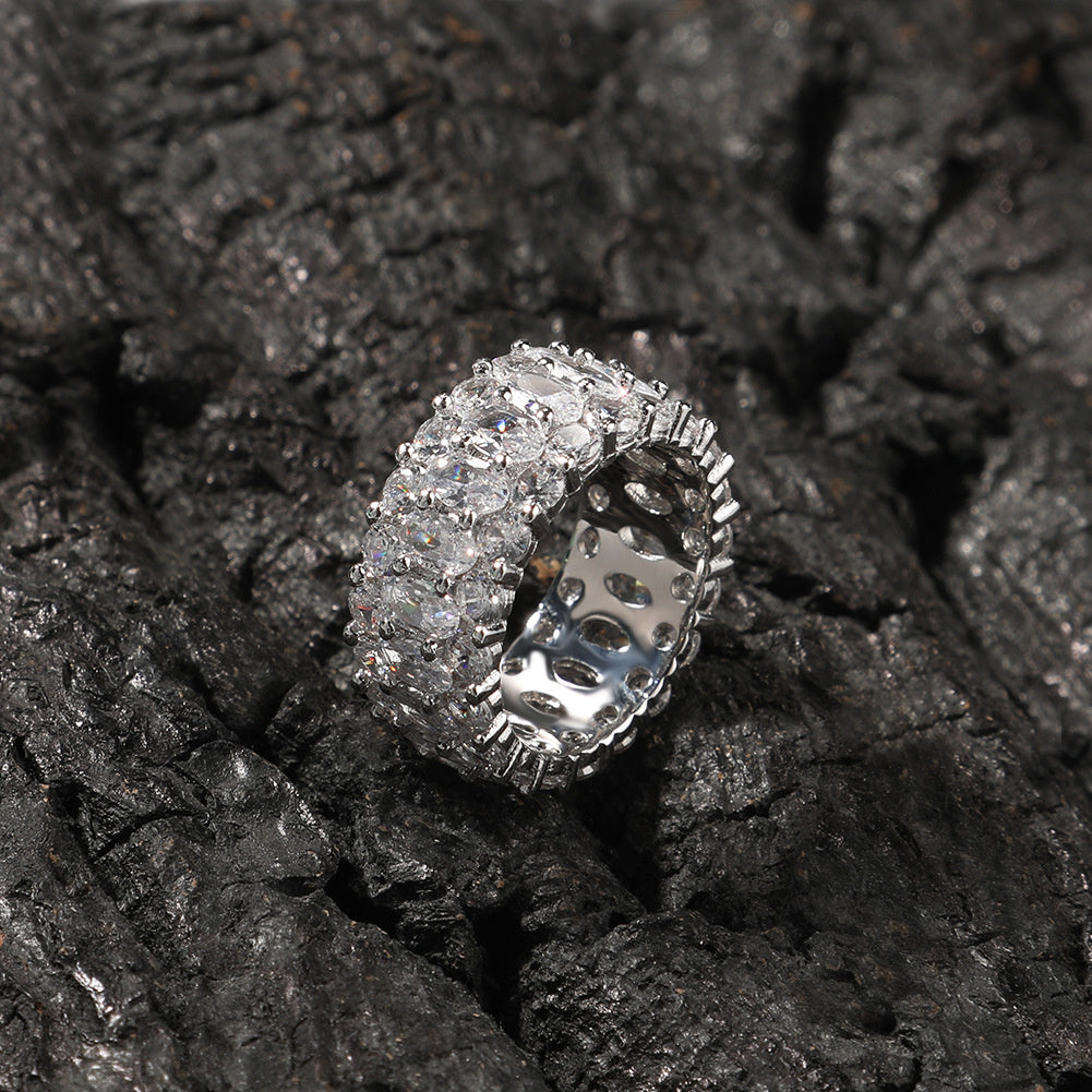 White-stone three-row oval ring displayed on black rocks