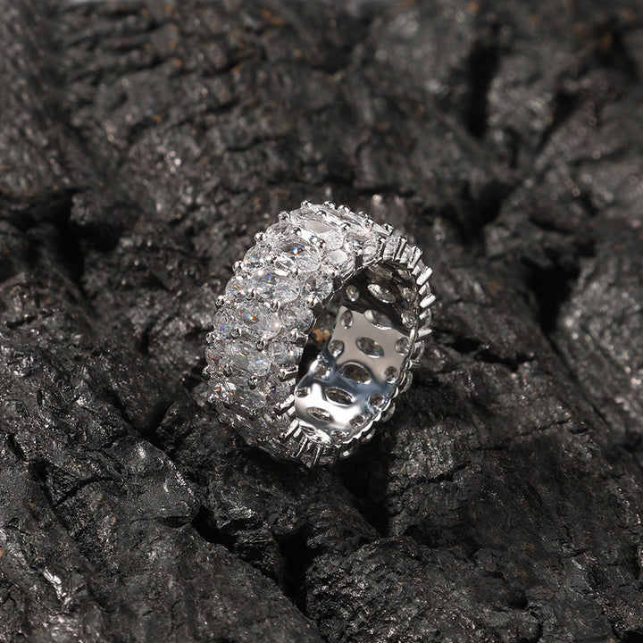 White-stone three-row oval ring displayed on black rocks