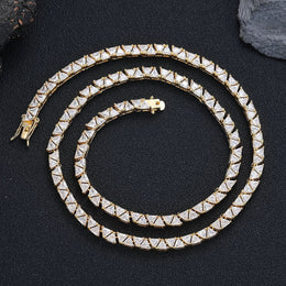 Gold-tone triangle tennis chain coiled on black fabric
