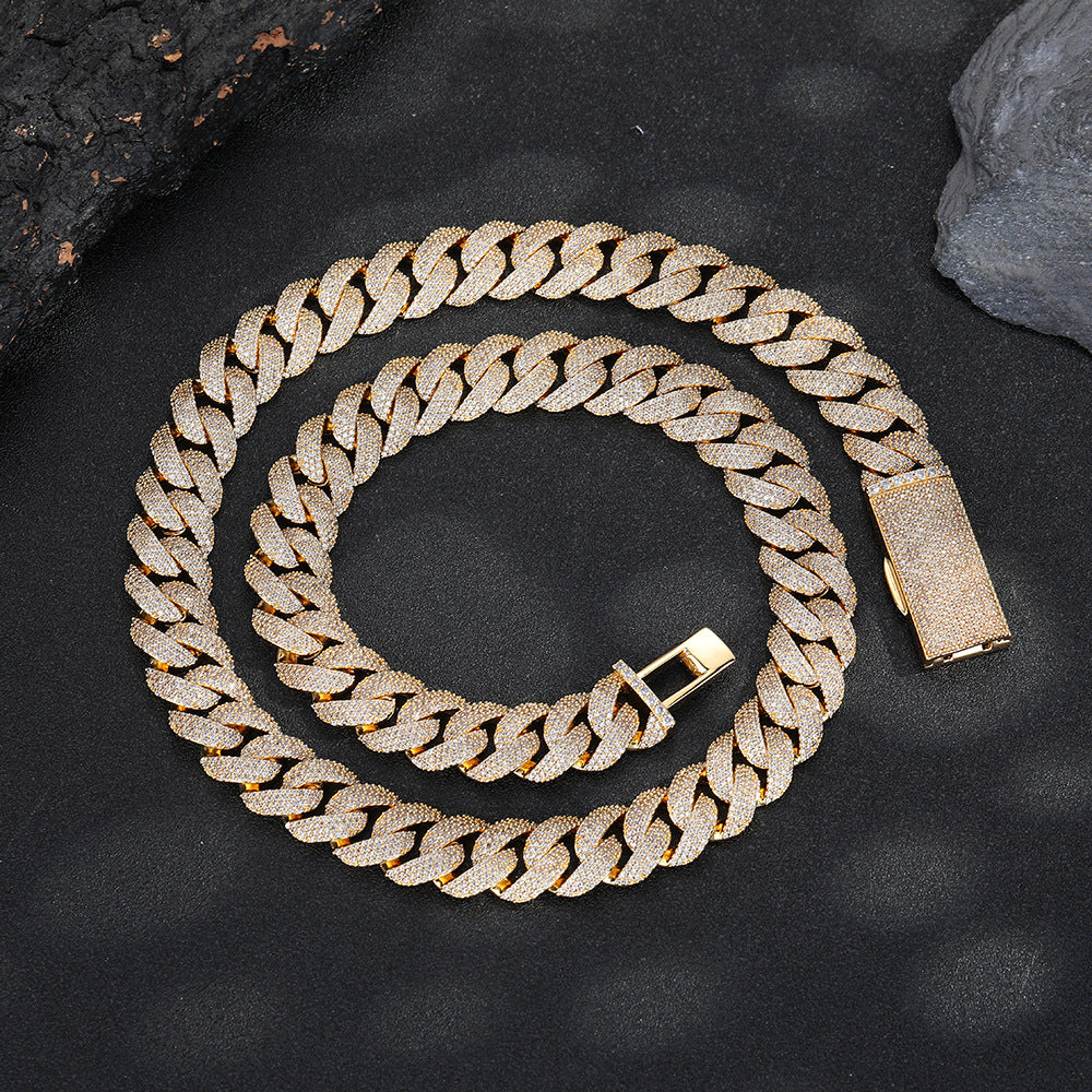 Gold-tone pavé Cuban chain coiled on dark stone with its clasp open