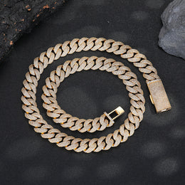Gold-tone pavé Cuban chain coiled on dark stone with its clasp open