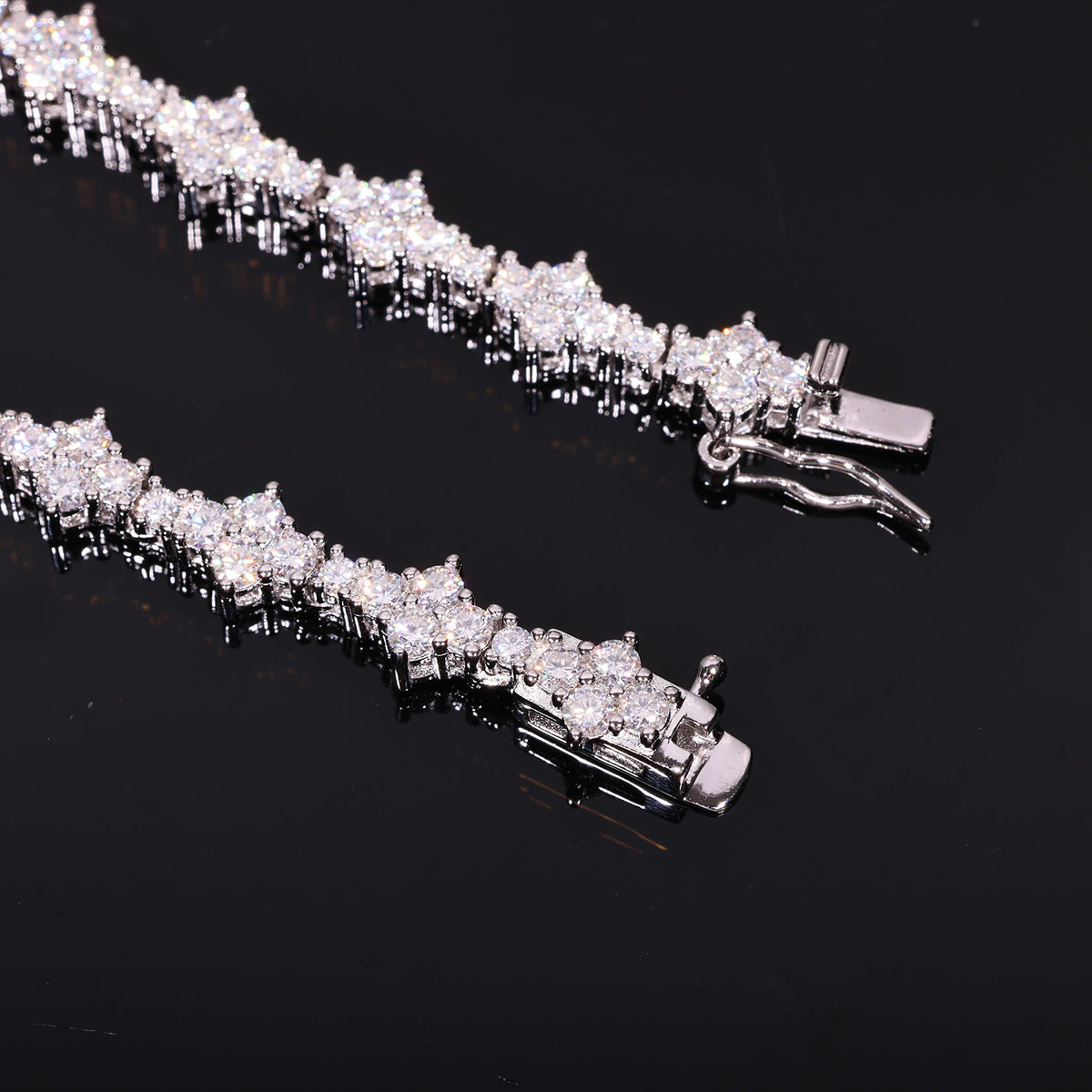 Close-up of round moissanite stones and the open box clasp on a silver-tone tennis chain