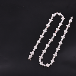 Silver-tone moissanite cross tennis chain arranged in an open loop on a dark surface