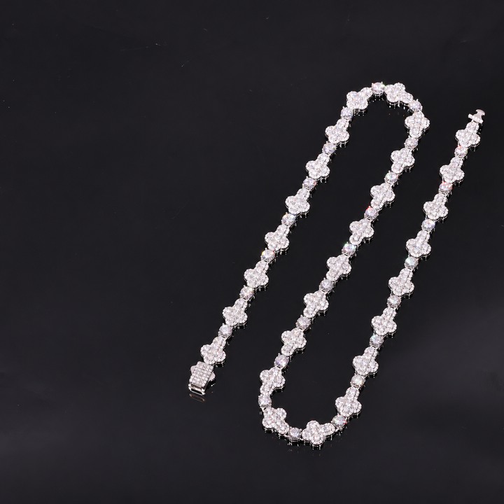 Silver-tone moissanite cross tennis chain arranged in an open loop on a dark surface