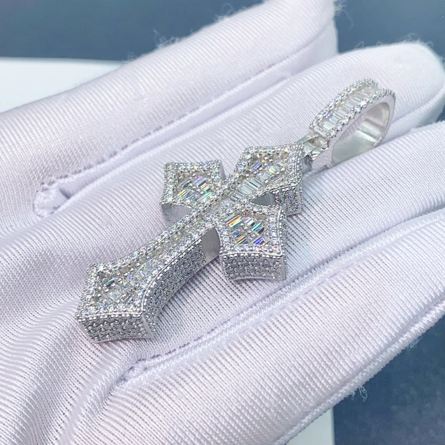 Silver iced Gothic Moissanite cross pendant held in white glove