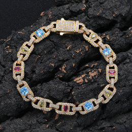 Gold-tone multicolor geometric link bracelet resting on a dark rock