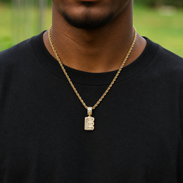 Gold iced baguette capital B initial pendant worn by a brown-skinned model