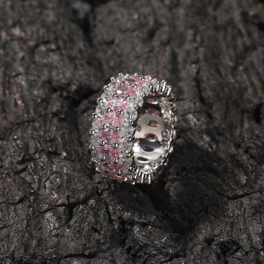 Pink-stone three-row oval ring displayed on black rocks