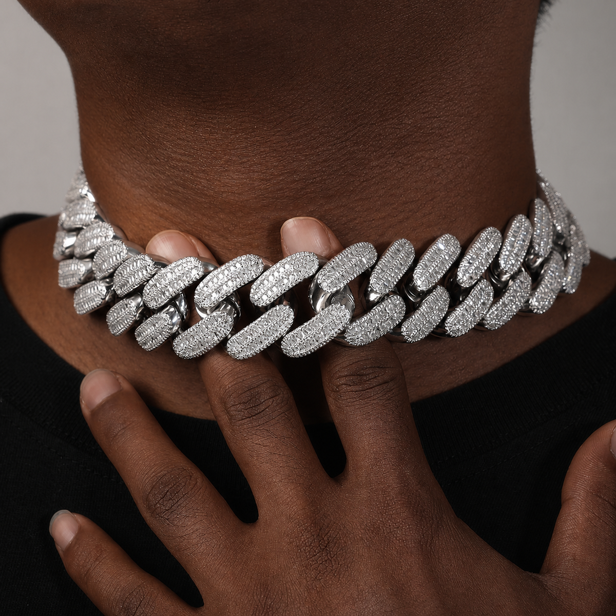 Silver 26mm iced Cuban chain worn by a deep-brown model