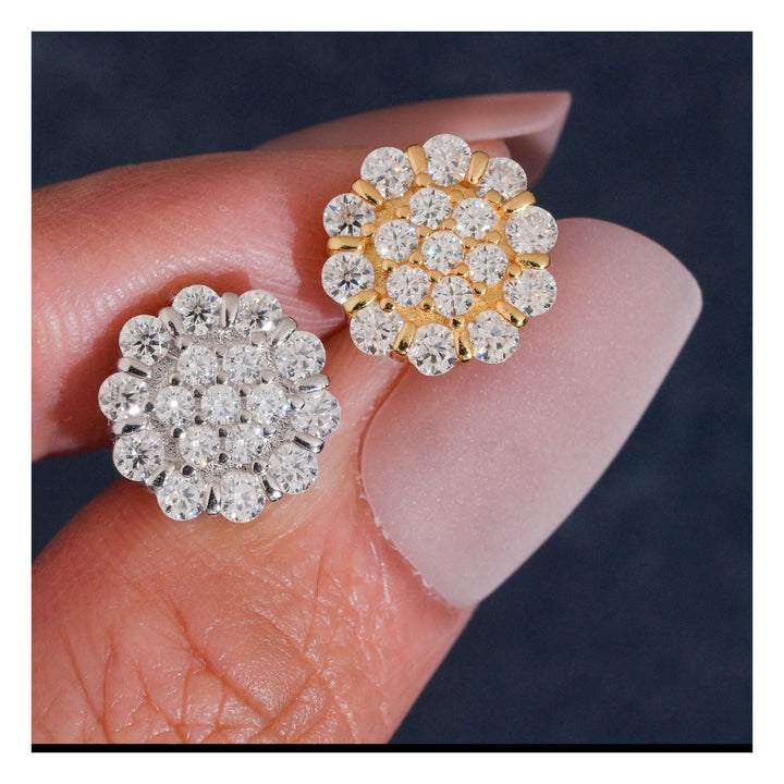 Silver-tone and gold-tone flower-cluster stud earrings held between fingers