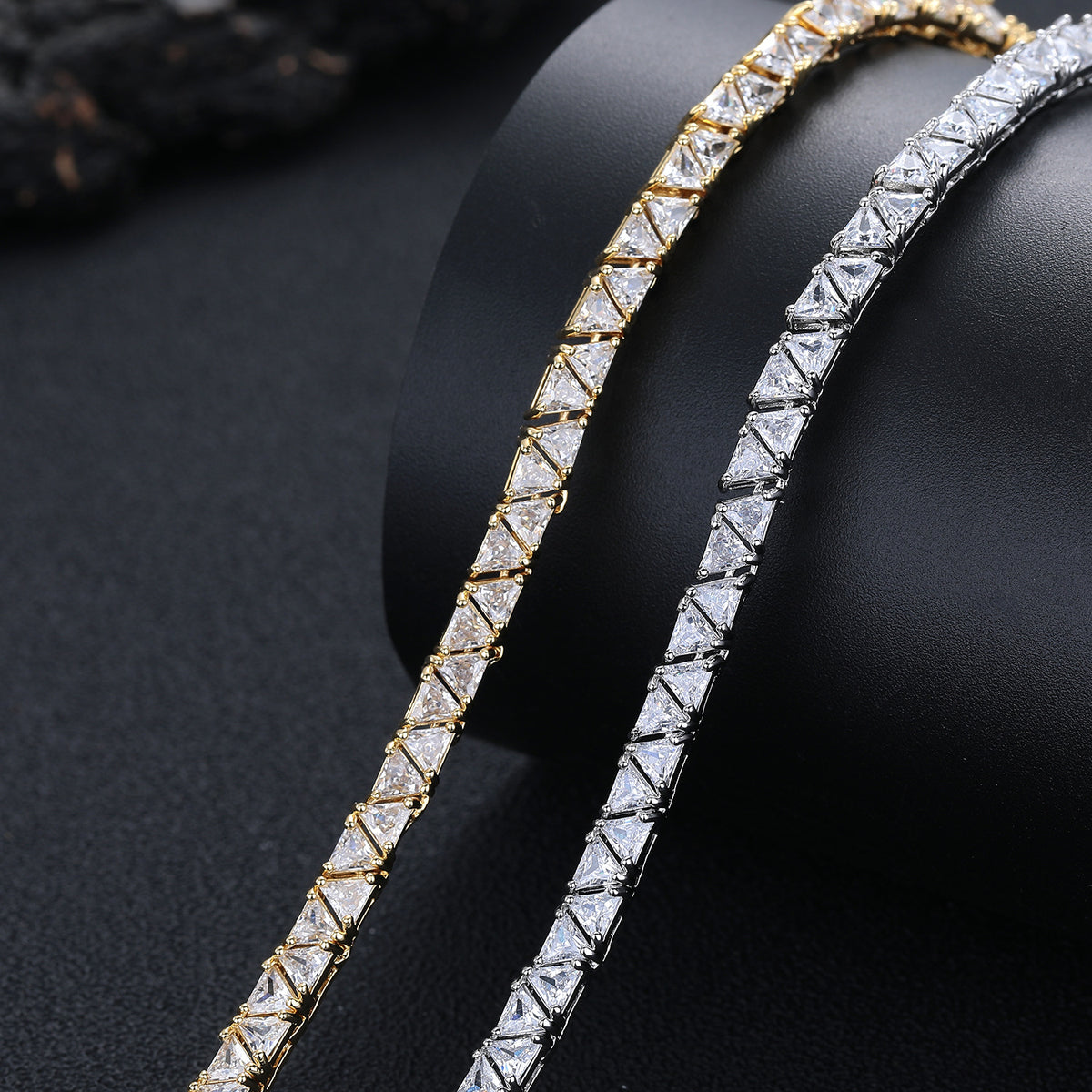 Close-up of triangular stones in silver- and gold-tone necklaces on a black bust