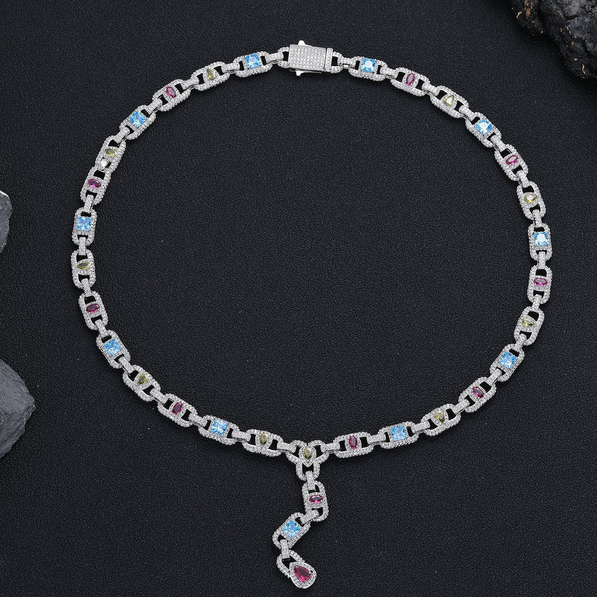 Silver-tone multicolor lariat necklace arranged in a circle on black fabric