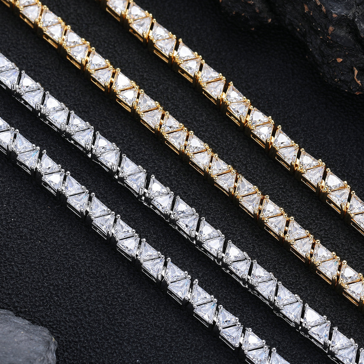 Silver- and gold-tone triangle stone settings viewed close up on black fabric