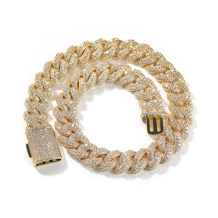 Gold-tone wide stone-set Cuban link necklace coiled on white