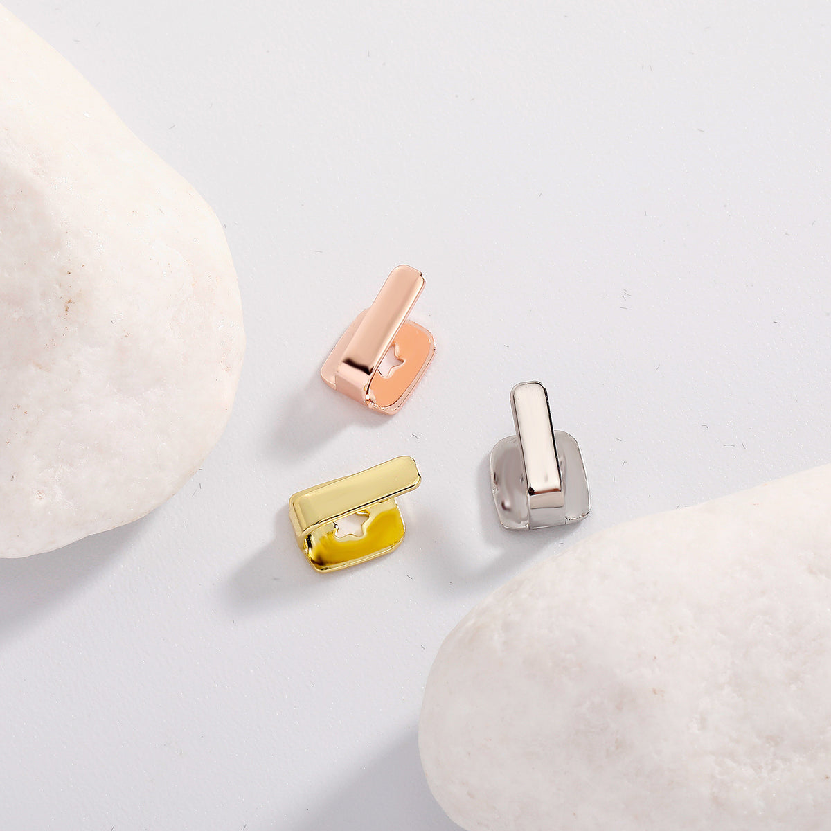 Rose Gold, Gold and Silver bar tooth caps arranged between pale stones