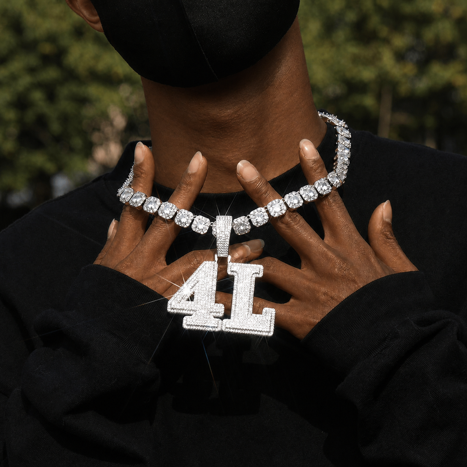 Deep brown skin model holding a silver custom AL iced pendant and tennis chain