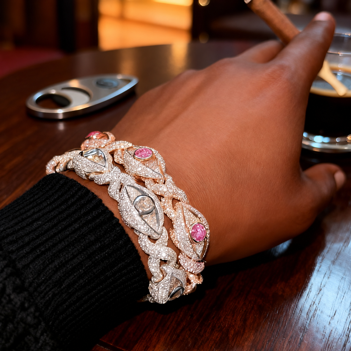 Rose-gold-tone pink eye bracelet layered with a different silver-tone bracelet beside a black sleeve