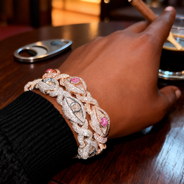 Rose-gold-tone pink eye bracelet layered with a different silver-tone bracelet beside a black sleeve