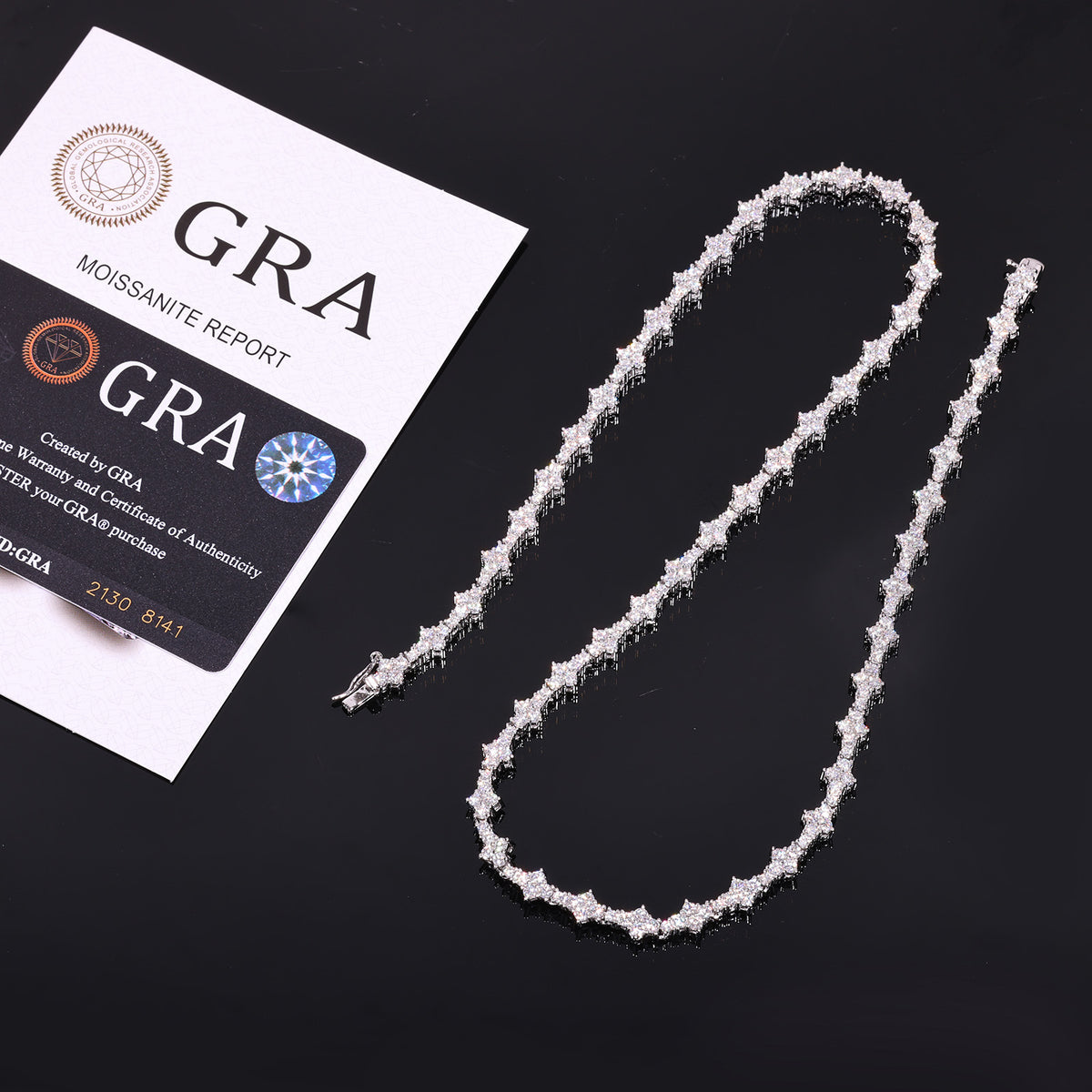 Silver-tone moissanite tennis chain beside a GRA report and card on black
