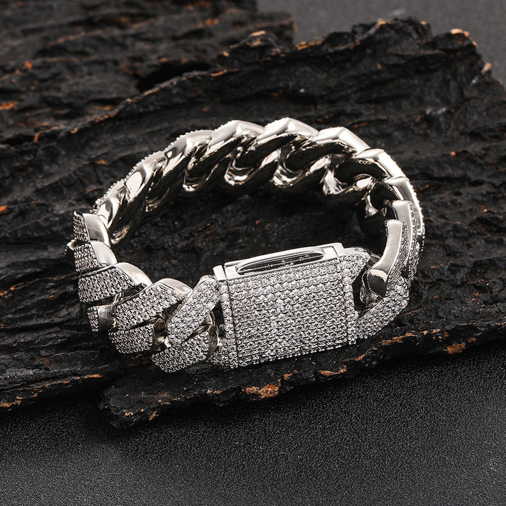 Silver-tone wide Cuban link bracelet with stone-covered clasp on dark textured wood