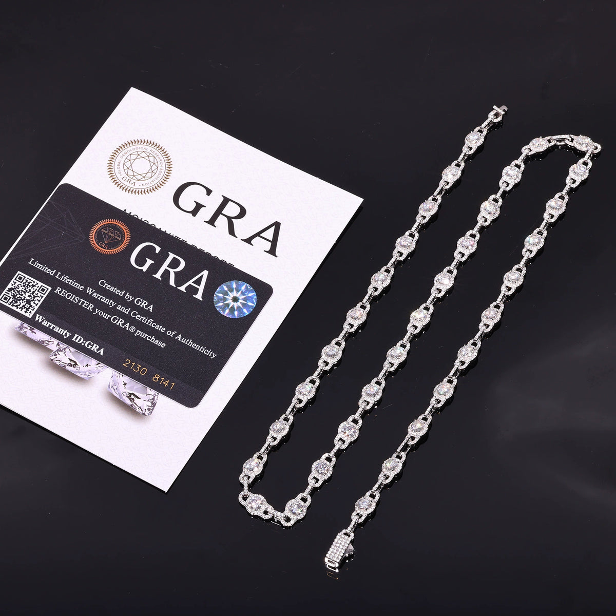 Silver-tone moissanite halo link chain beside GRA report papers on a dark surface