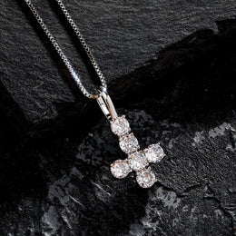 Silver iced inverted cross pendant displayed on black stone