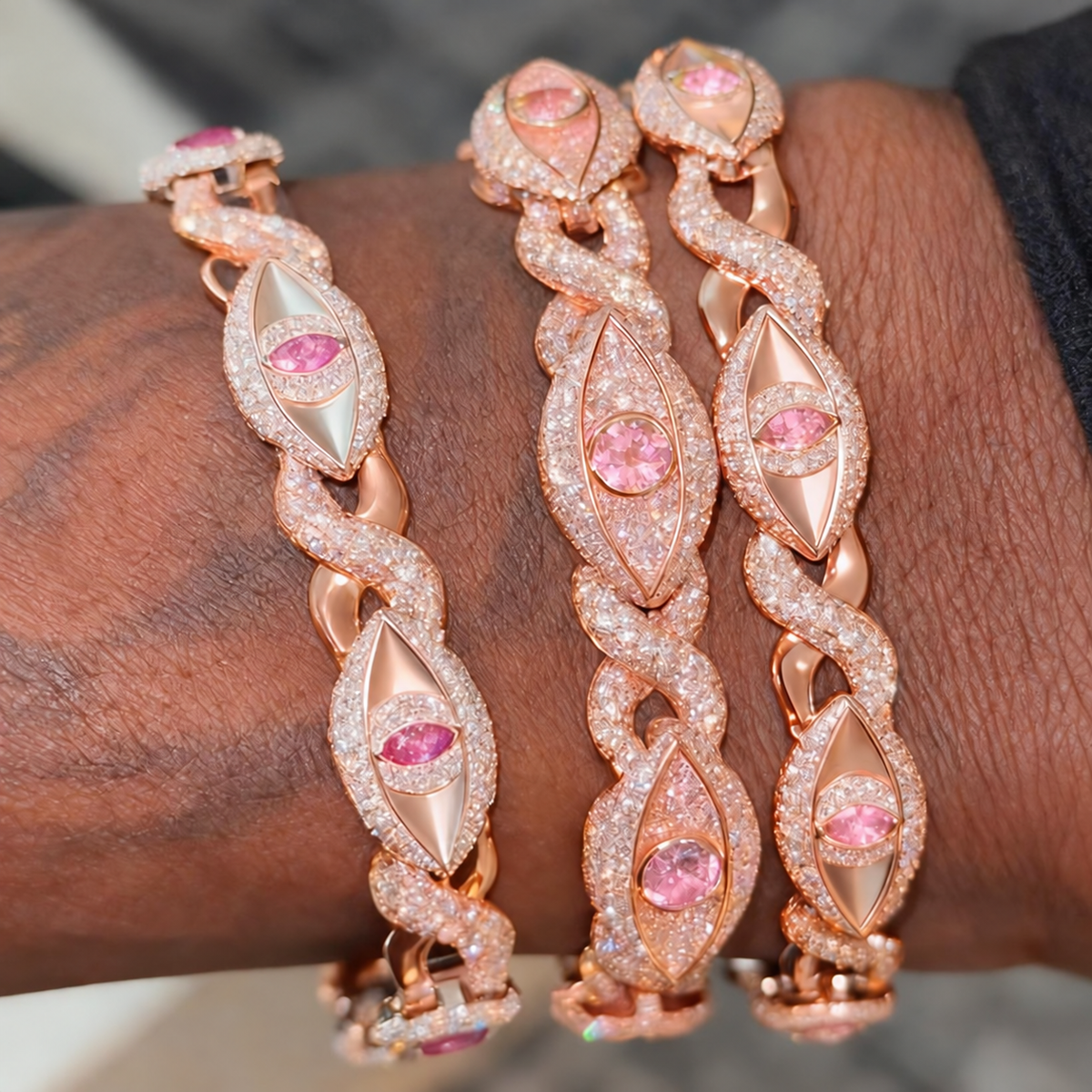 Pink round-centered eye infinity bracelet in the middle of three bracelets worn together