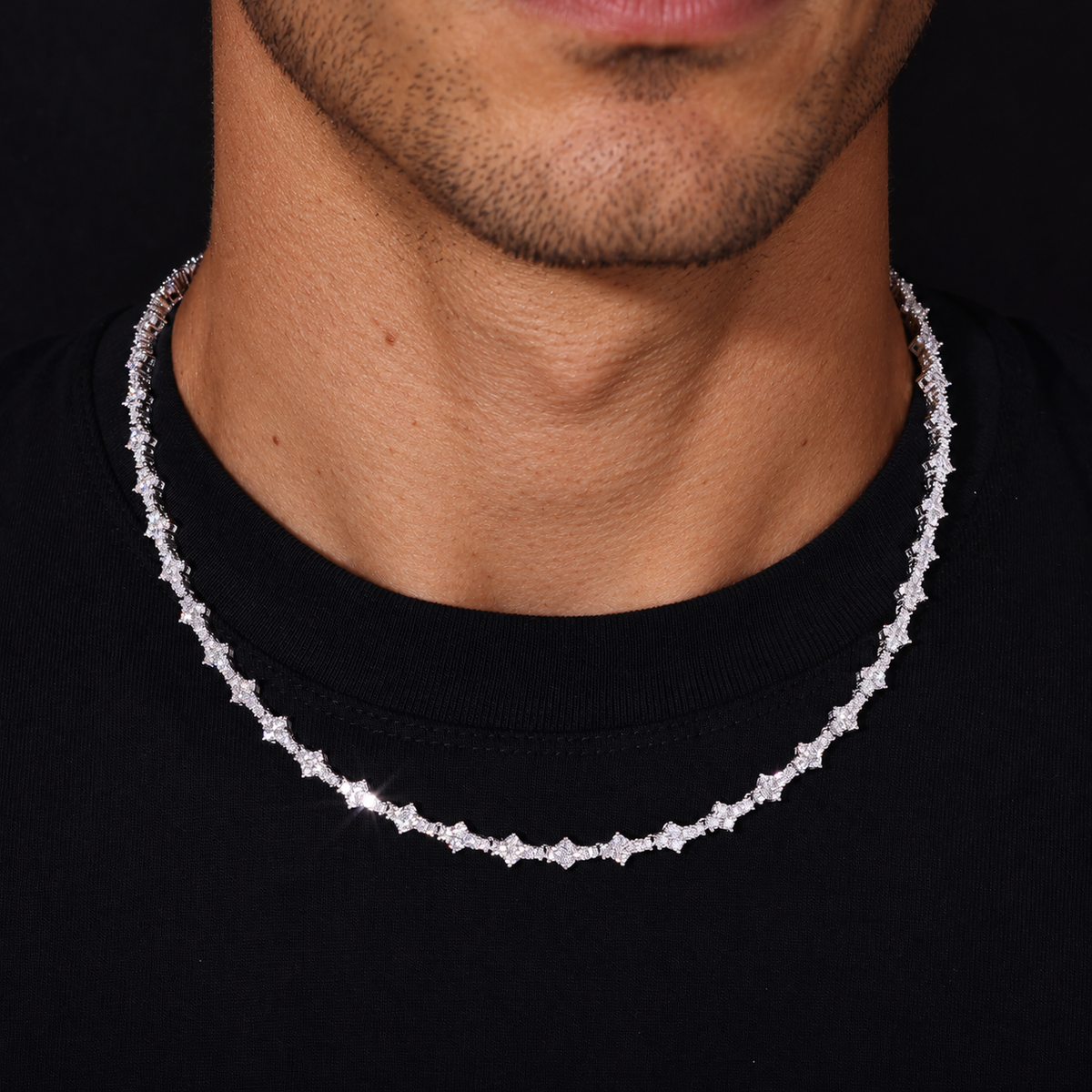 Adult model wearing a silver-tone moissanite tennis necklace over a black crew-neck shirt