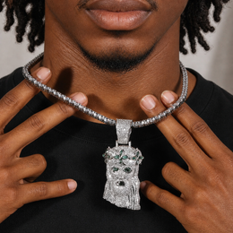 Silver-tone crowned portrait pendant held by a brown-skinned model