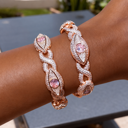 Two rose-gold-tone eye bracelets layered on a wrist outdoors