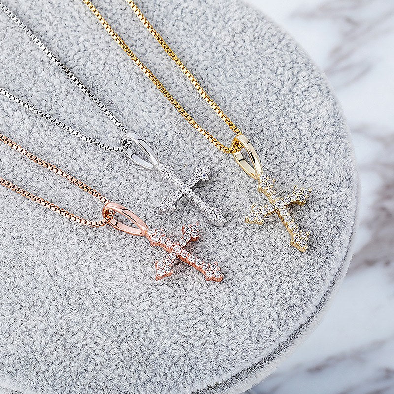 Silver gold and rose gold cubic zirconia cross pendants displayed together