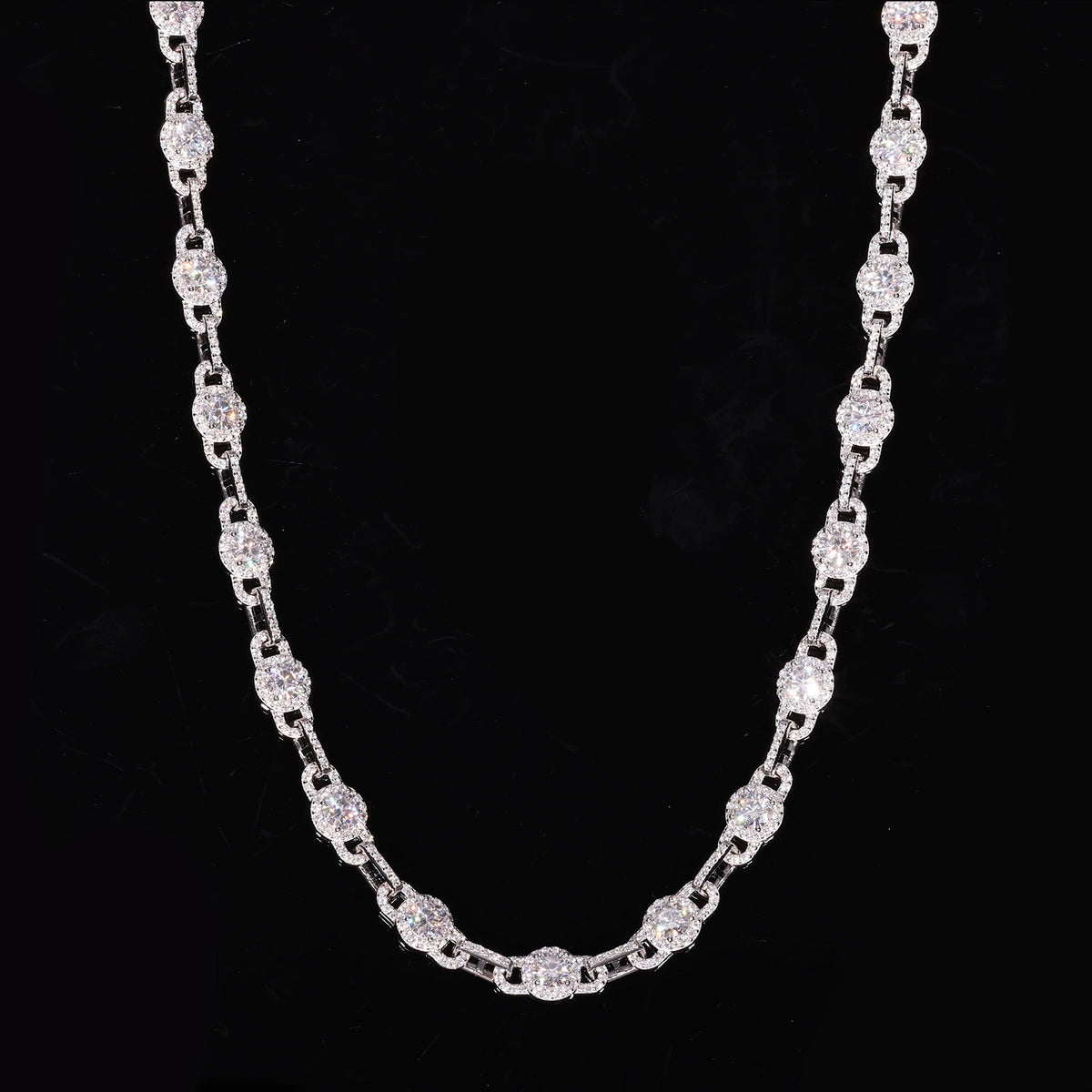 Round moissanite halo links alternating with slim connectors in a U-shaped drape on black