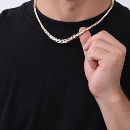 Adult model lifting a gold-tone graduated tennis necklace over a black crew-neck shirt