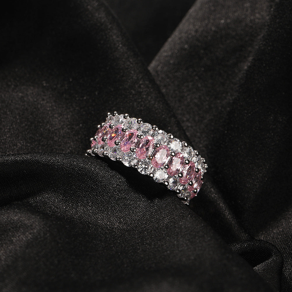 Pink-stone three-row ring resting on black fabric