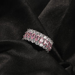 Pink-stone three-row ring resting on black fabric