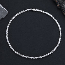 Silver-tone triangle tennis chain arranged in a circle on black fabric