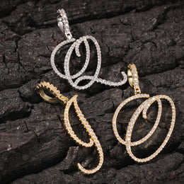 Gold-tone and silver-tone cubic zirconia script letter pendants on bark