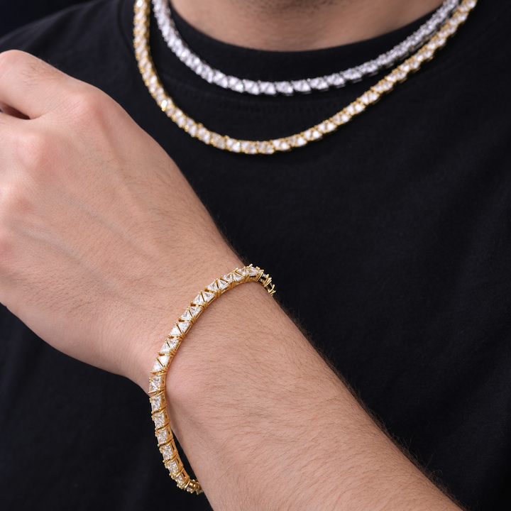 Adult model wearing a gold-tone triangle tennis bracelet against a black shirt