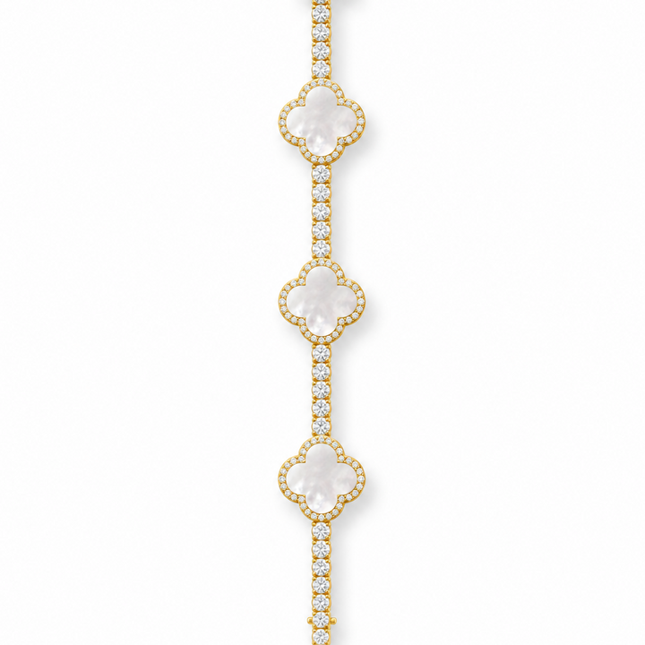 Gold-tone tennis bracelet with pearlescent white clover inlays displayed open on white